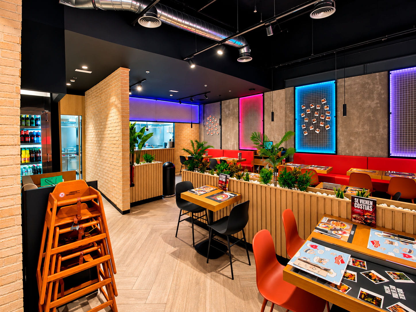 Sala con techo negro, cuadros de neón y bancos rojos