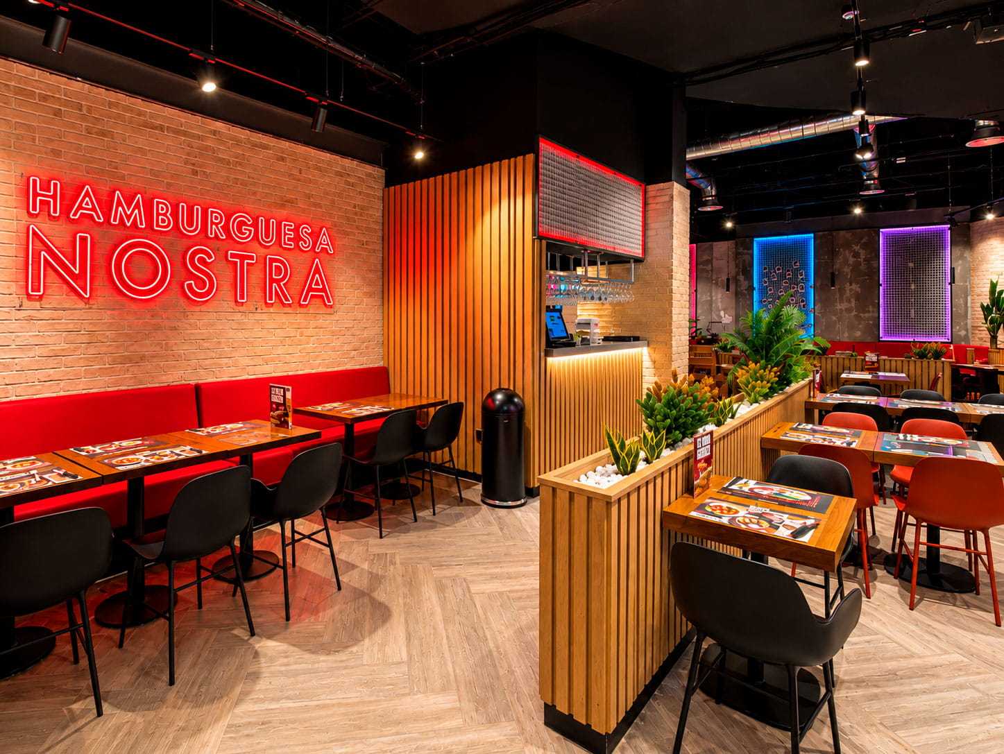 Comedor con rótulo de neón Hamburguesa Nostra sobre ladrillo