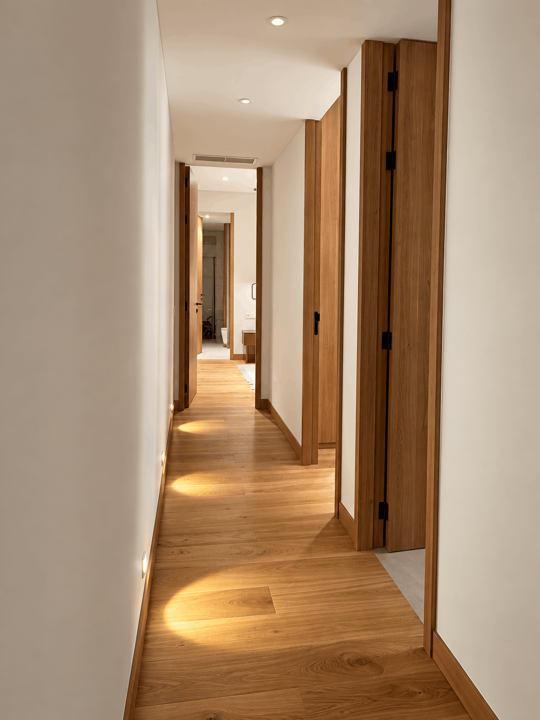 Pasillo con suelo de madera y puertas de roble