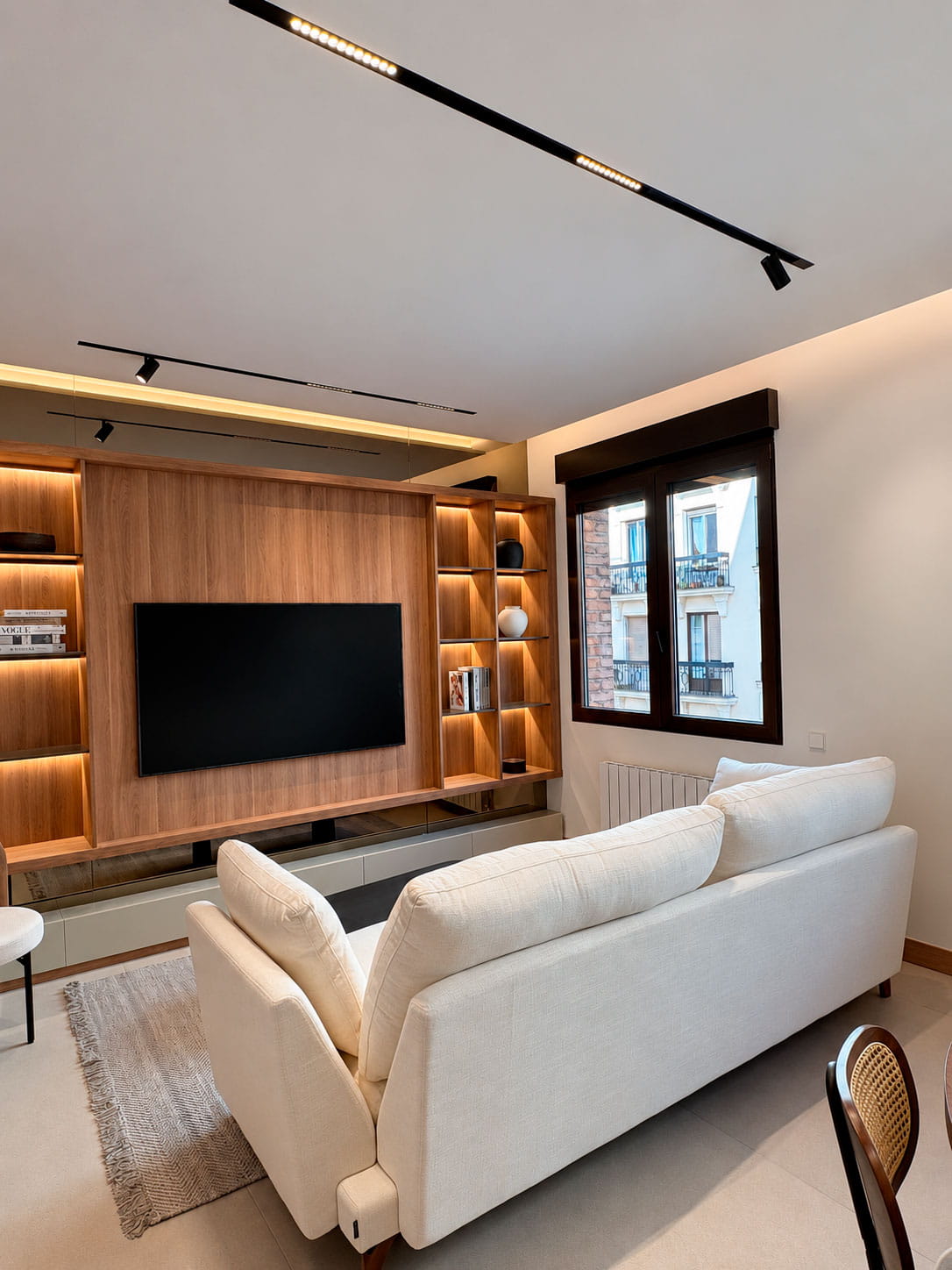 Salón con mueble de madera retroiluminado y sofá blanco